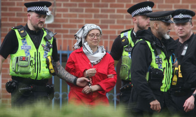 A woman in a Palestinian keffiyeh is arrested by British police