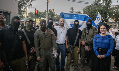 A group of masked and armed people pose with two Israeli legislators