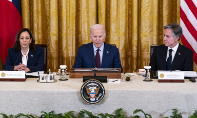 Kamala Harris, Joe Biden and Antony Blinken seated with flags behind them