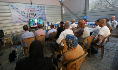 A group of people sit watching a monitor