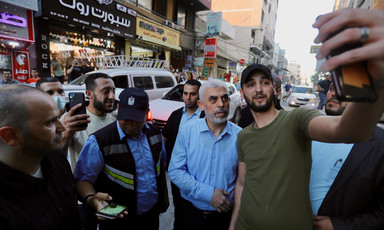 Yayha Sinwar surrounded by people in a street smiles for a selfie