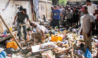 In daytime, men sift through the rubble and debris in the aftermath of an Israeli airstrike.