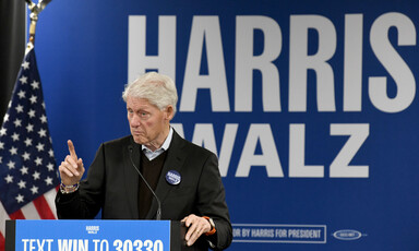 Former President Bill Clinton speaks in Milwaukee, Wisconsin in front of a Harris-Walz sign and an American flag