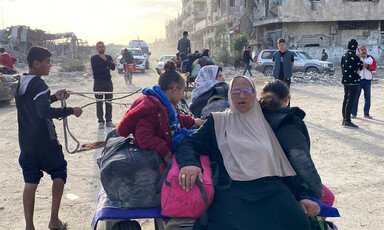 A number of people sit on a cart amid a scene of destruction in Gaza 