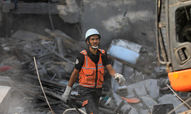 A man in hi vis vest walks through rubble