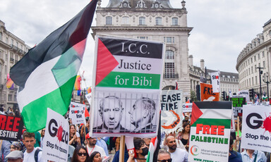 A protester holds a sign with a Palestine flag and mug shot of Netanyahu readingg "ICC justice for Bibi"