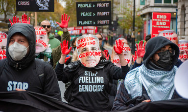 Protesters wear masks of political leaders and t-shirts saying Stop Fuelling Genocide 