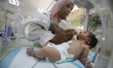 A baby is being fed milk inside an incubator