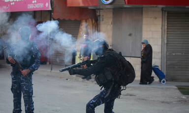 An armed and masked man points his rifles amid a cloud of smoke