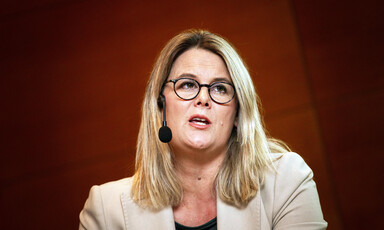 Woman seen from chest up speaks while wearing a headset microphone