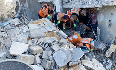 Emergency workers look through the rubble of a house