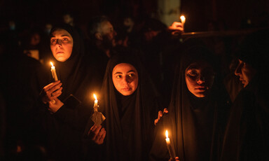 Dark clad girls hold up candles