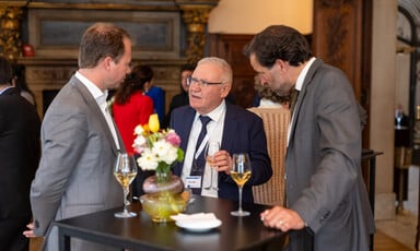 Israel's Amos Yadlin holds a glass of wine as he chats to two other men 