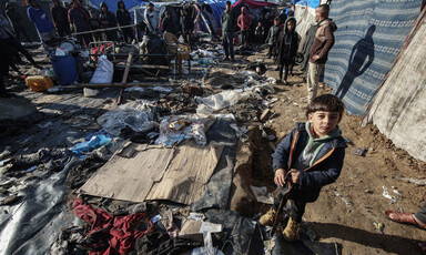 A boy stands next to a destroyed tent