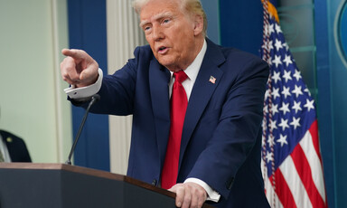 President Donald Trump points from podium with American flag behind him