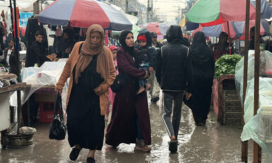 People walk through a market in the rain