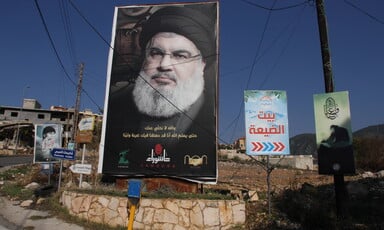 A large poster of Hasan Nasrallah displayed on a street corner