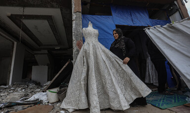 A woman stand next to a mannequin wearing a wedding dress