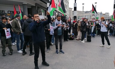 A man speaks surrounded by protesters holding flags and placards in Brussels