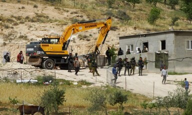 A Hyundai bulldozer and numerous Israeli troops beside a family's home in the occupied West Bank