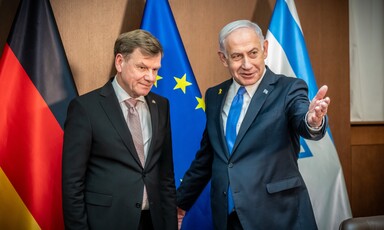 German Foreign Minister Johann Wadephul and Israeli Prime Minister Benjamin Netanyahu stand in front of flags 