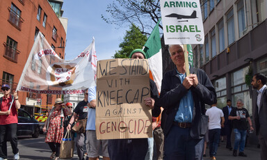 A man holds up a placard voicing support for Kneecap against genocide