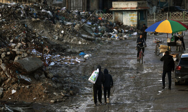 People wal;k past mountains of waste in Gaza