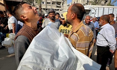 A group of men hold a body wrapped in a shroud. One of the men is weeping.