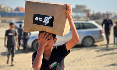 A boy carries a box as he and others seek aid