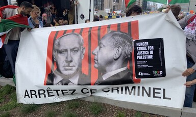 A banner featuring a photograph of the Israeli Prime Minister with a moustache similar to that of Adolf Hitler and a slogan reading Arrêtez Ce Criminel, French for Arrest This Criminal.