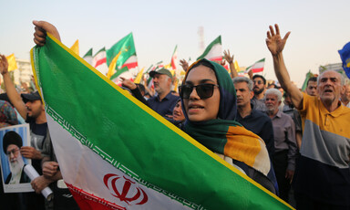 Woman surrounded by people holds Iranian flag