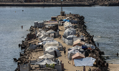 A jetty filled with two rows of tents extends into the ocean.