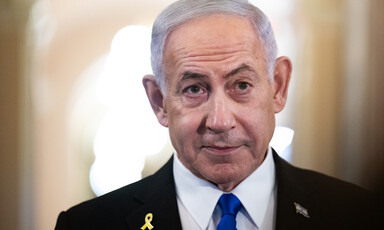 Israeli Prime Minister Benjamin Netanyahu stands with a yellow ribbon and Israeli flag lapel pin on his suit jacket
