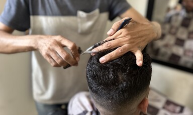 One man cuts another man's hair 