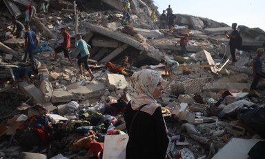 A woman walks past the rubble of a bombed tower block