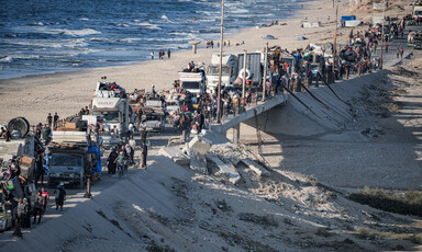 People walk beside a long convoy of trucks on the Gaza coast 