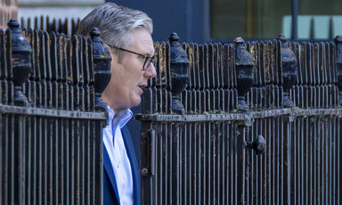 UK Prime Minister emerges from a metal fence