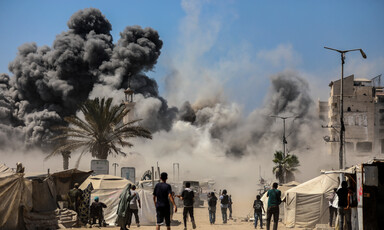 Palestinian bystanders watch smoke billow over Gaza City following an Israeli attack