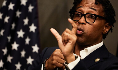Congressman Wesley Bell gesticulates with an American flag near him