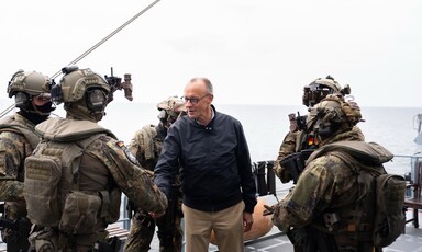 German Chancellor Friedrich Merz shakes hand with a uniformed soldier as other uniformed soldiers stand beside him