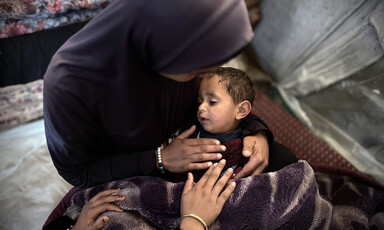A woman seen from above cradles a baby in her lap