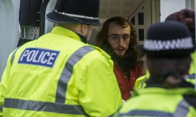 A man being put into a van by UK police