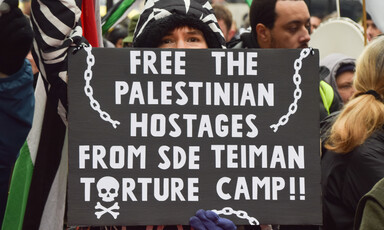 Woman at demonstration holds sign reading "Free the Palestinian hostages from Sde Teiman torture camp"