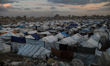 A sea of tents on the backdrop of the ruins of a city