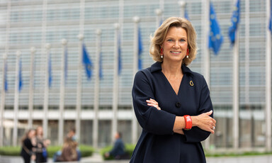 The European Union's Coordinator Against Anti-Semitism Katharina von Schnurbein stands with her arms folded outside a building with poles to which blue and yellow flags are attached 