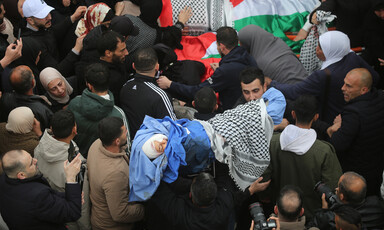 Crowds of mourners gather around the bodies of the Bani Odeh family, wrapped in shrouds, Palestine flags and keffiyehs