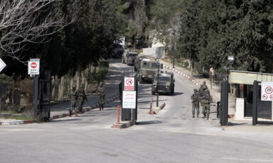 Soldiers and military vehicles move up a road