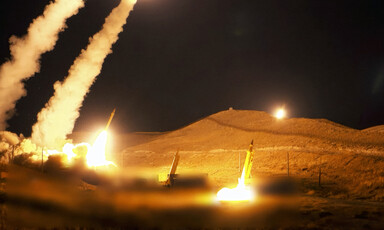 Several missiles launched at night trail smoke and fire