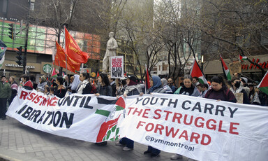 A large number of people can be seen behind a banner reading Youth Carry the Struggle Forward 