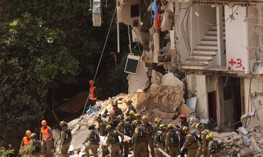 Group of men in helmets work in rubble